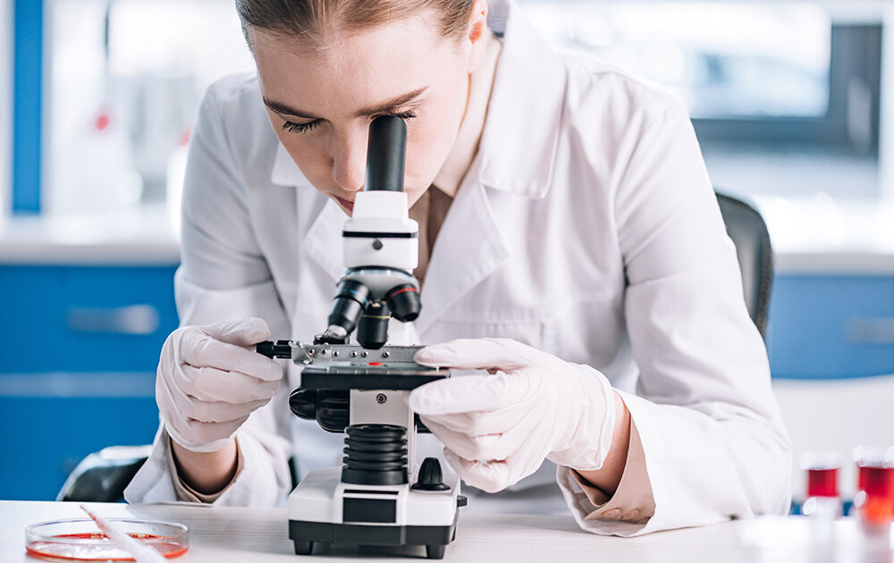 woman looking through microscope