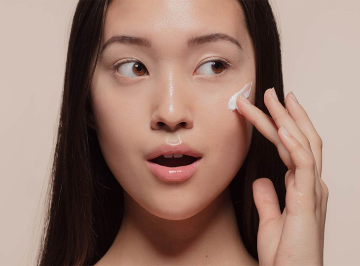 Close-up of woman applying skin cream to her cheek