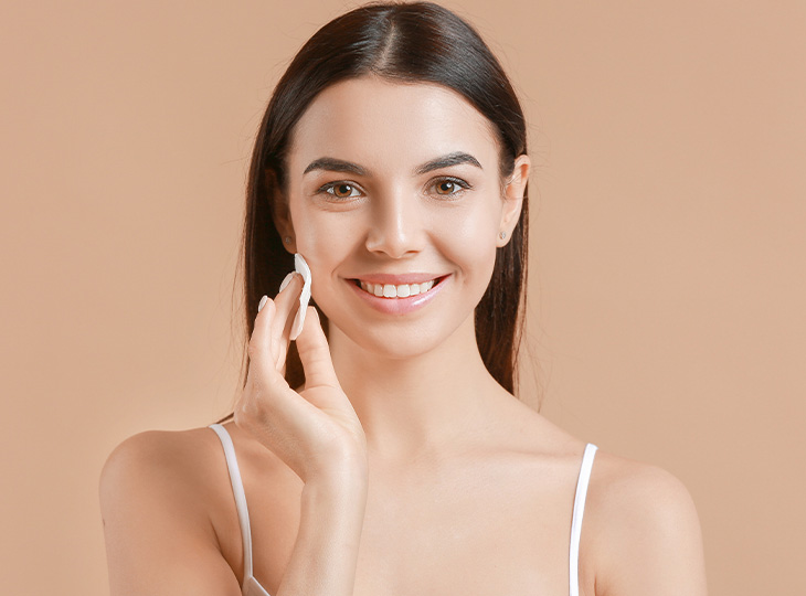Woman with healthy skin touching her face with a cotton swab