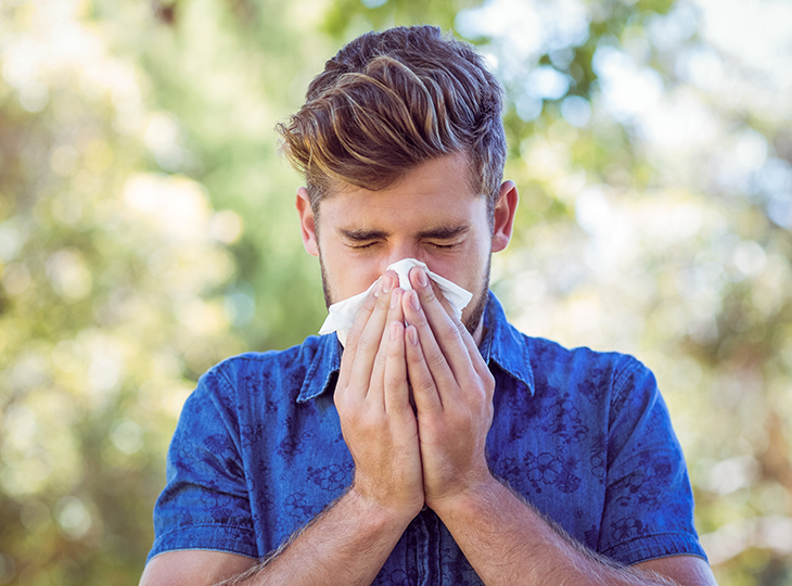 Man in a blue shirt blowing his nose